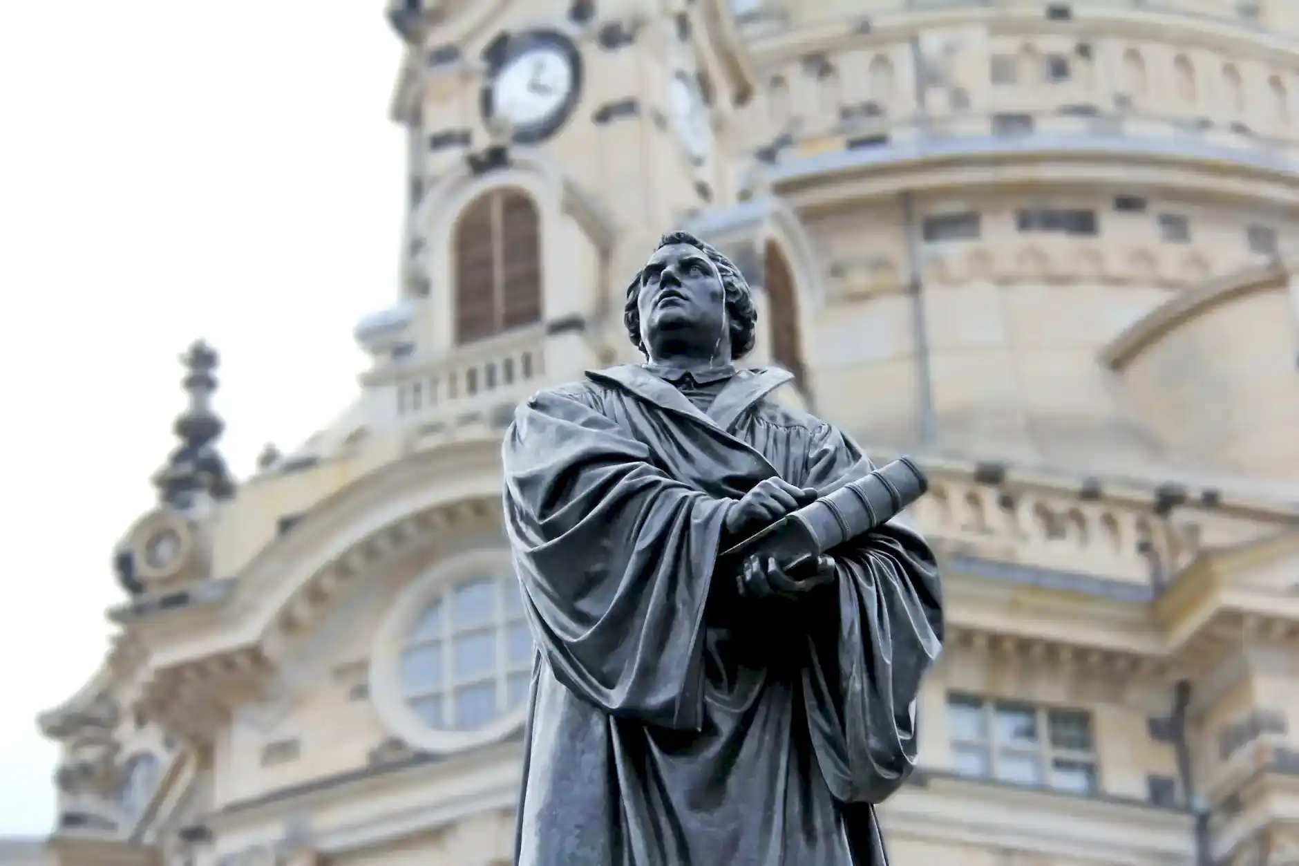gray concrete statue of man holding book beside brown building
